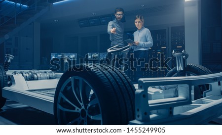 Automobile Mae and Female Design Engineers Working on Electric Car Platform Chassis Prototype, Using CAD Software for 3D Concept. In Automotive Innovation Facility Vehicle Frame with Tires, Suspension