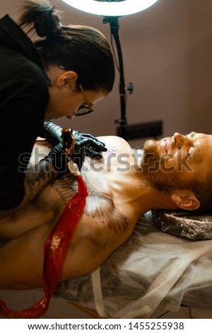 Tattoo salon process. A tattoo girl stuffed a tattoo. the process of stuffing a tattoo on the body. Hands close-up.