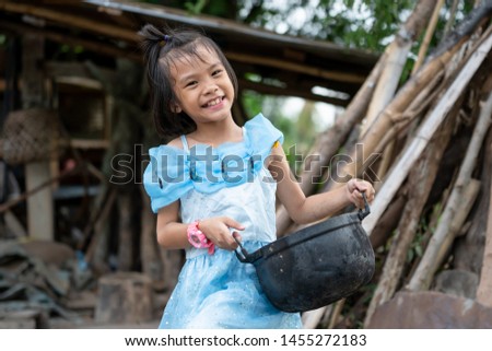 Asian kids holding food pot on blurred old wooden house background on daytime sunny, children girl smiling and happy on countryside in Thailand, pretty and cute child in culture rural lifestyle 