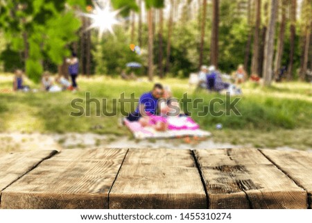 Table top background and blurred sunny garden forest view in distance. Empty space on the table top for an advertising product.