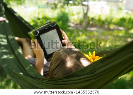 Young beautiful girl in hammock reading e-book. Pretty woman leisure lifestyle portrait at nature ountdoor. Female relax in forest. Adorable teen expressive face. Tourism in summer camp.