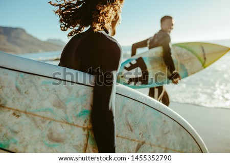 Two young men with surfboard going for surfing in the sea. Surfers carrying surfboards running on the beach. Royalty-Free Stock Photo #1455352790