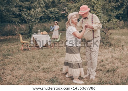 A grandfather with happy eyes looks grandmother in the eyes. Youth memories. The concept of a happy old age. Portrait of oldies who are dancing in the garden Royalty-Free Stock Photo #1455369986