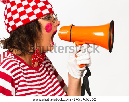 Funny clown in eyeglasses with necktie shouting at the megaphone, view in profile over white background.