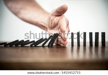 Domino Falling and Intervention / Chain Reaction Royalty-Free Stock Photo #1455412715