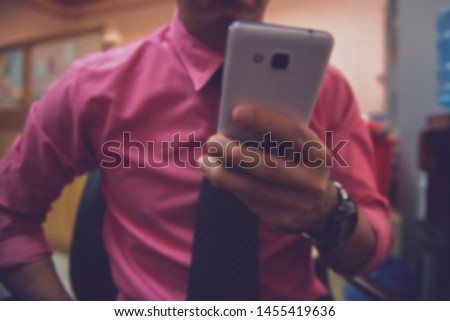 Men holding a phone.Men playing games on the phone.(This picture is soft focus.This picture is blurry blurred.Blurry concept))