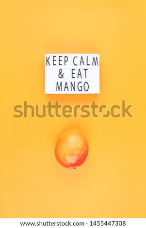 Mango fruit in creative conceptual top view flat lay composition with lightbox with Keep calm and eat mango slogan isolated on orange background in minimal style with copy space. Pop art poster