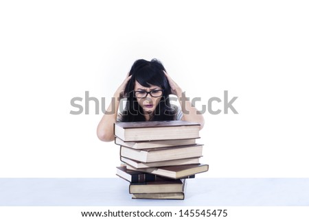 Asian female student stressing out looking at books on white background