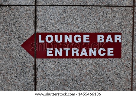 Lounge bar entrance. Panel with arrow on a marble wall.