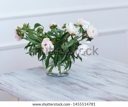 peony flowers standing in a glass vase on the table