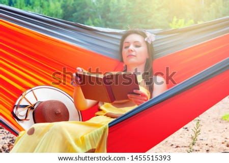 Beautiful woman with a book in a hammock on a background of beautiful nature