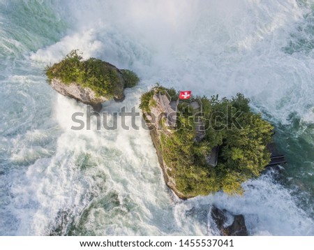 Aerial view of rocks in rhine fall water cascade near Schaffhausen with swiss flag in Switzerland