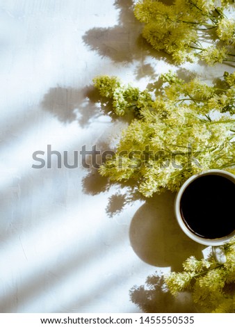 Cup of coffee and wild flowers on light background, top view. Cozy Breakfast. Flat lay .
