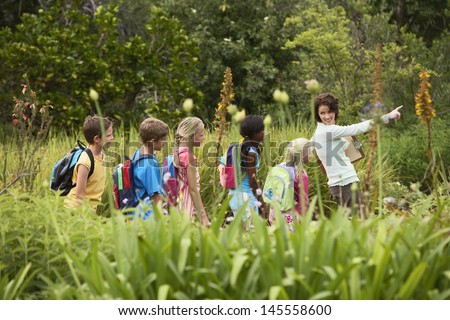 Young teacher with children on nature field trip Royalty-Free Stock Photo #145558600