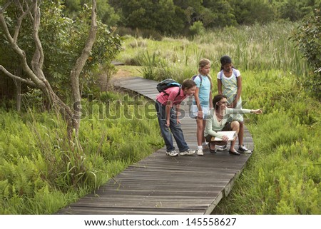 Teacher showing something to children during nature field trip Royalty-Free Stock Photo #145558627