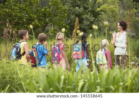 Young teacher with children on nature field trip Royalty-Free Stock Photo #145558645