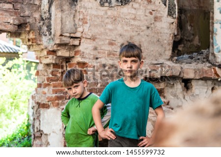 Two sad and unhappy brothers in a destroyed and abandoned building, staged photo.
