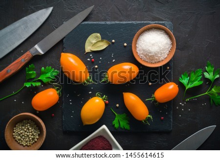 Fresh and juicy orange tomatoes laid out on a dark stone background. View from above. Place for text