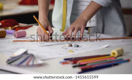 Designer drawing template for sewing new dress according to her sketches