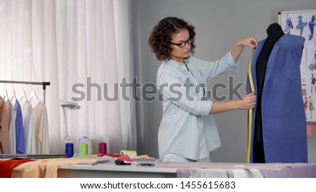 Stylist working on coat, measuring length of collar and thinking how decorate it