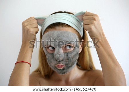 Bubbling mask with charcoal oxygen purifying product on the face of beautiful woman. Skin care mask. Funny headband with ears
 