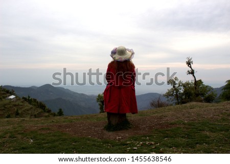 A girl is sitting on mountain and feeling the love of the nature. Wearing coat and an amazing cap