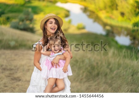young mother and daughter walking through a rural area with a beautiful landscape