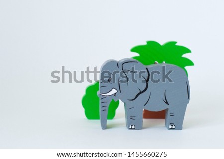 Children's wooden toys on the table. Elephant near spalsy and bush