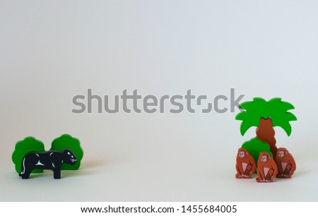 Children's wooden toys on the table. The monkeys are next to bed with spears and the panther in the bushes. On a white background