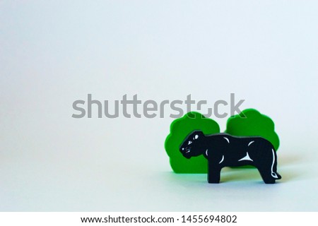 Children's wooden toys on the table. Panther near the bushes on a white background