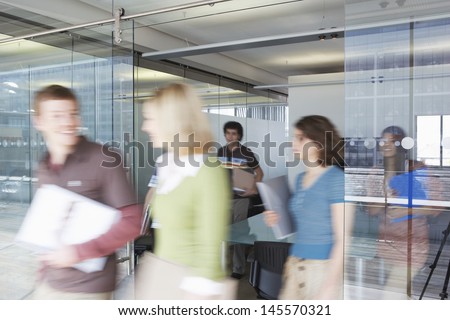 Multiethnic blurred office workers leaving conference room Royalty-Free Stock Photo #145570321