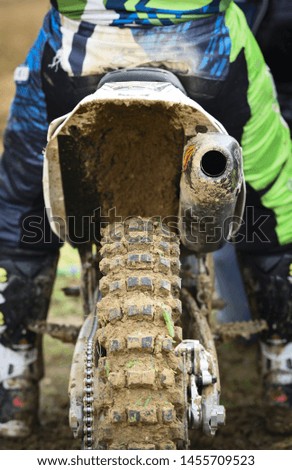 Unrecognized Athlete riding a sports motorbike and muddy wheel on a motocross racing event