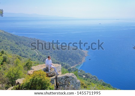 The photo was taken in Turkey in one of the Princes' Islands. The picture shows a young guy admiring the sea from the height of the cliff.