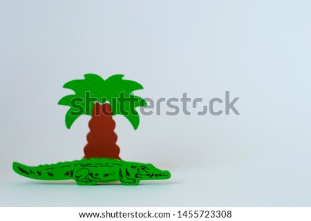 Children's wooden toys on the table. Crocodile near the palm tree on a white background
