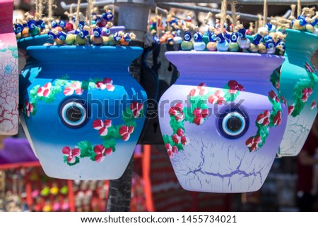 Decorative colorful small buckets sold in the store. Blueand purple color hanging with ropes. There are evil eye beads inside.