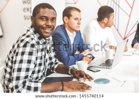 A team of young office workers, businessmen with laptop working at the table, communicating together in an office. Corporate businessteam and manager in a meeting. coworking.