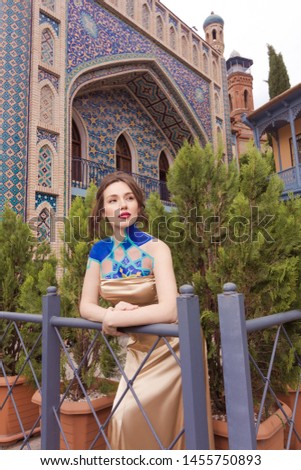On the streets in Tbilisi in Georgia, public places. Brunette girl posing on the background of a wall with blue mosaic.