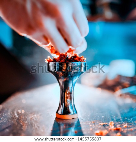 Process of making hookah for smoking. concept of smoking a hookah and having a good time. laying tobacco in a hookah bowl close up view. Toned image Royalty-Free Stock Photo #1455755807