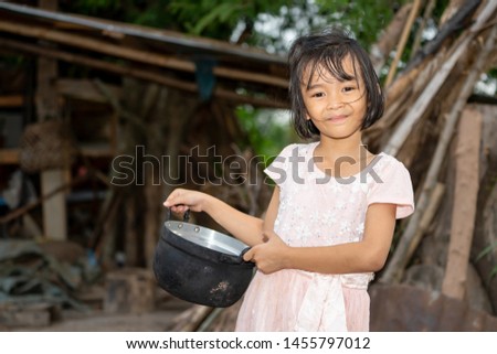 Asian kids holding food pot on blurred old wooden house background on daytime sunny, children girl smiling and happy on countryside in Thailand, pretty and cute child in culture rural lifestyle 