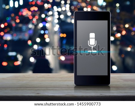 Microphone flat icon on modern smart mobile phone screen on wooden table over blur colorful night light traffic jam road and cars in city, Business communication online concept
