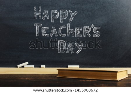 Black chalk board over wooden table with book, blank for text or background for school theme.