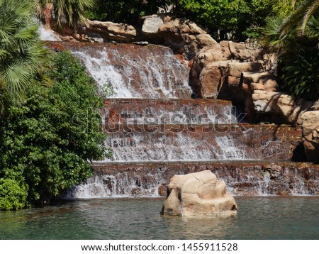 Water cascades down a man-made waterfalls in a landscaped garden