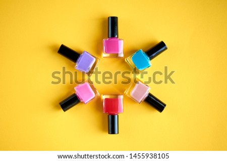 Color nail polish bottles on yellow background composition. Flat lay and top view photo