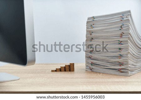 Step pile of gold coins with stack of overload paperwork report of sale on wooden table have blur computer on foreground with white background and copy space. Business and finance concept success.