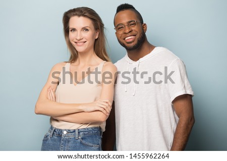 Smiling African American man in glasses and Caucasian woman posing for photo together, diverse friends in casual clothes, boyfriend and girlfriend looking at camera, isolated on studio background