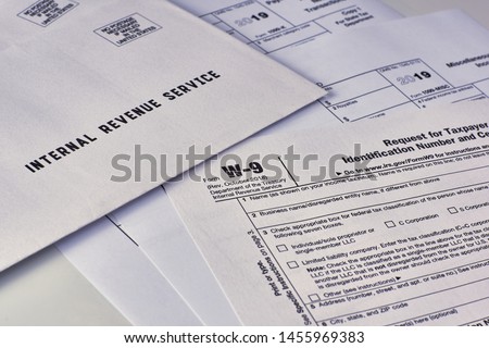 Three mails from the Internal Revenue Service lie on tax Form w-9, 1099-misc, 1099-k on a white background Royalty-Free Stock Photo #1455969383