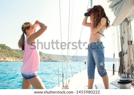 Beautiful teenagers using photographic camera, luxury private sailing yacht on summer holiday, taking pictures modelling outdoors. Fun activities, aspirational leisure recreation technology lifestyle.