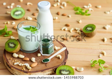 Organic summer breakfast with superfood spirulina, yogurt, kiwi, mint and nuts on wooden table. Meal that promotes good digestion and functioning of gastrointestinal tract. Healthy food concept. Royalty-Free Stock Photo #1455988703