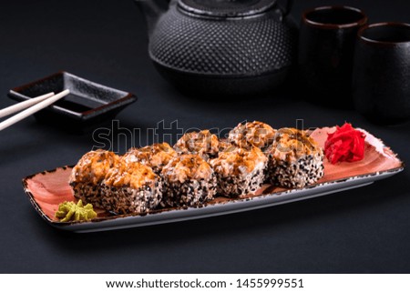 Top view close up of assorted sushi set with salmon, shrimp, caviar, mussels, tuna, cream cheese and hot sauce and chopsticks, soy on black background. Japanese sashimi raw food menu.