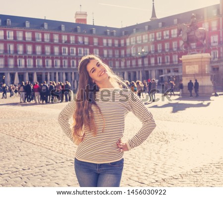 Beautiful happy young woman excited having fun in Plaza Mayor Madrid, Spain. Looking cheerful and delighted enjoying sightseeing and posing for picture. In tourism, European city and travel in Europe.